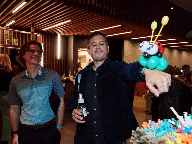 A guest at a corporate event showing off the ladybug balloon bracelet Michael twisted for him