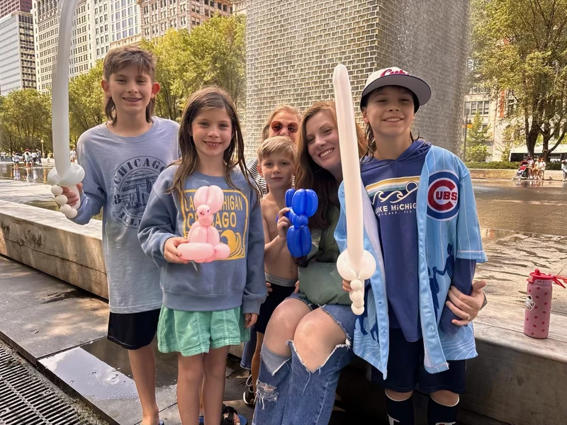 Kids and a mom smiling with the balloon swords and balloon animals Michael twisted for them