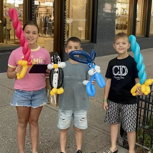 Young siblings with their balloon swords, a penguin, and a bunny