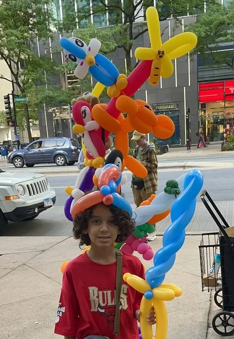 A boy with a balloon hat and Minecraft-style balloon sword on Michigan Avenue, Labor Day weekend 2026