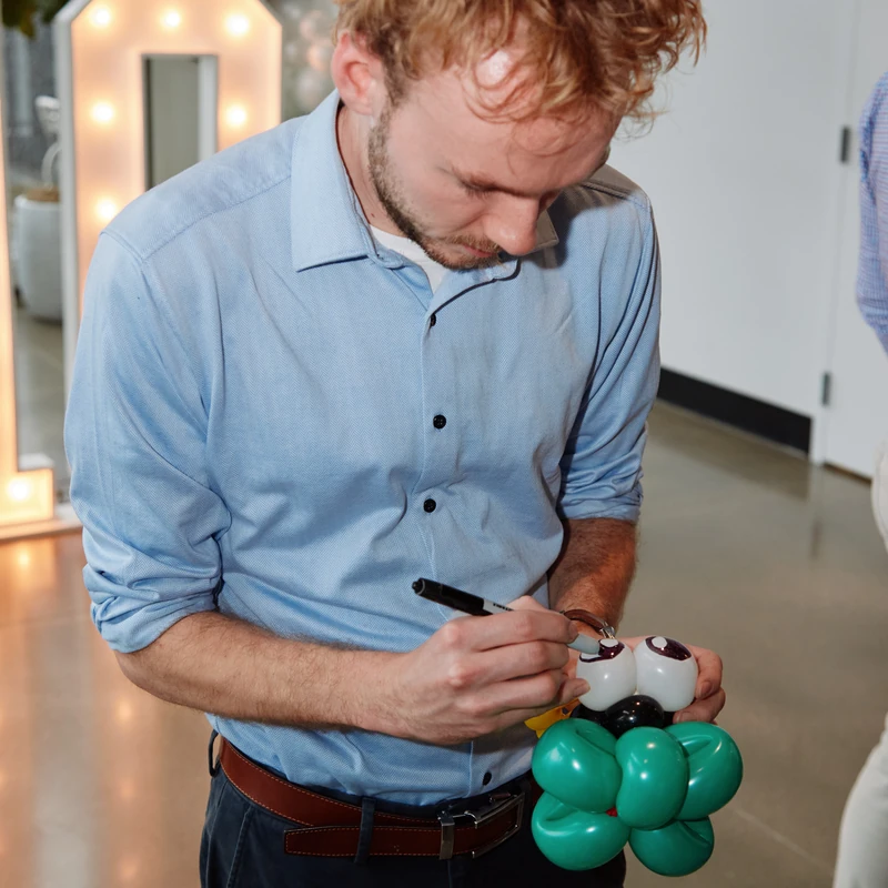Michael Romani drawing eyes on a ladybug balloon animal at a corporate event