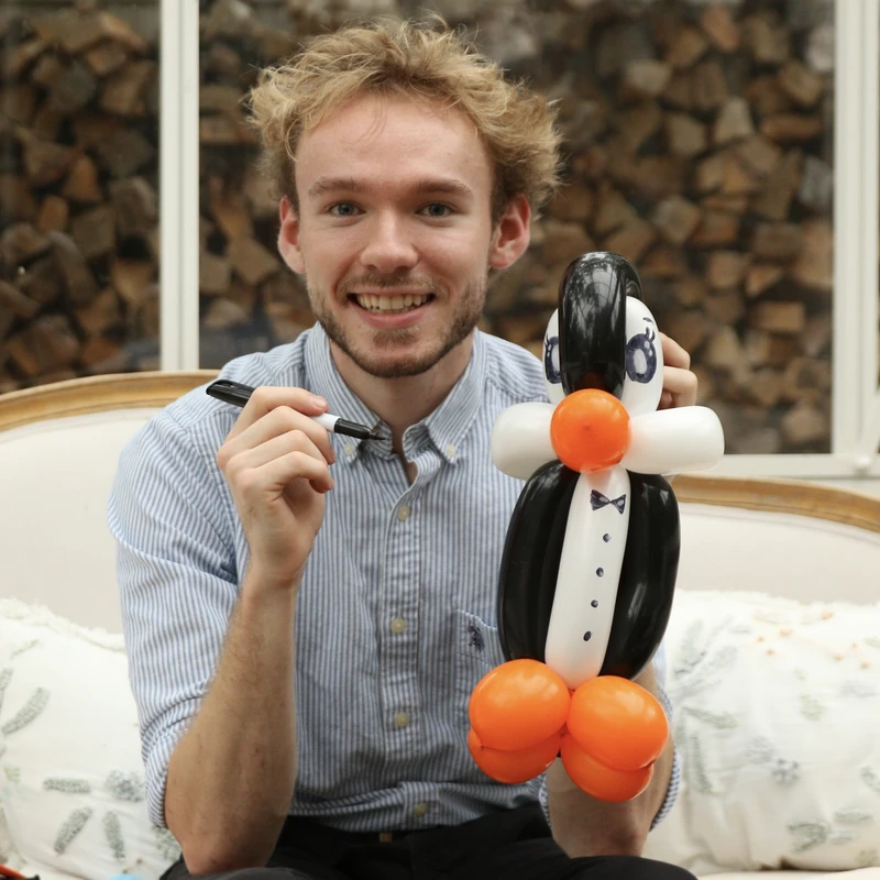 Michael Romani holding a finished penguin balloon animal