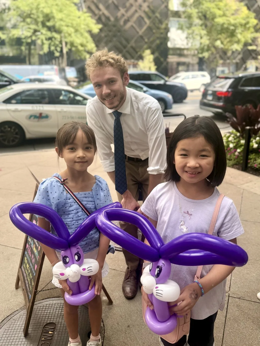 Michael Romani with two young girls and their purple balloon bunnies